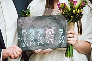 Newlywed couple is holding in hands picture of their future family they dream of