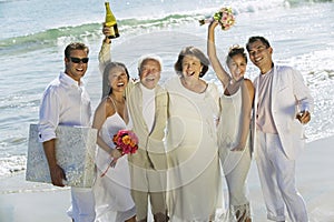 Newlywed Couples With Family Celebrating On Beach