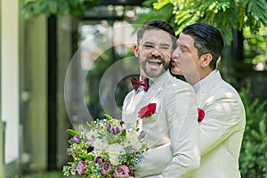 Newlywed gay couple hugging and kissing on wedding day celebration