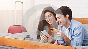 Newlyweds booking hotel using phone and credit card