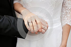 The newlyweds, the bride and groom hold hands with wedding rings