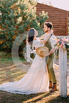 Newlyweds in cowboy style standing and hugging on ranch