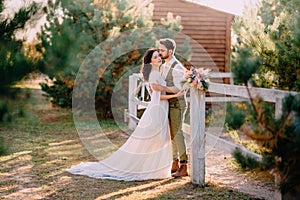 Newlyweds in cowboy style standing and hugging on ranch