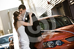 Newlyweds embracing against a wedding car