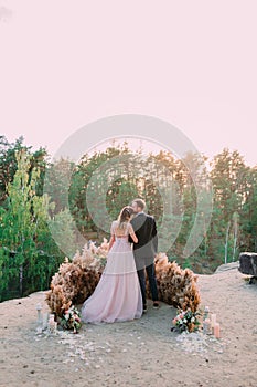 Newlyweds embracing at the edge of the canyon with tenderness and love. Back view. Outdoors wedding