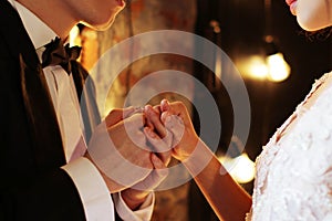 Newlyweds exchange rings, groom puts the ring on the bride`s hand in marriage registry office. Dark brown background photo