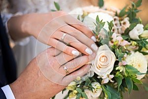 Newlyweds ` hands with rings. Wedding bouquet on the background of the hands of the bride and groom with a gold ring