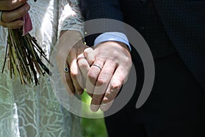 The newlyweds' hands were intertwined, displaying their wedding rings against contrasting attire, symbolising unity and love