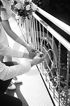 The newlyweds hang an iron lock on the railing of the bridge, as a symbol of eternal love