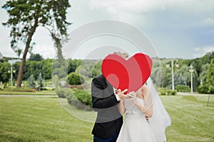 Newlyweds holding a decorative heart.