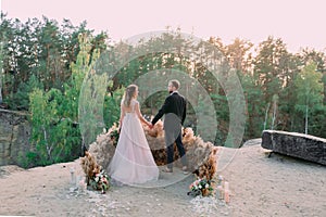 Newlyweds holding hands at the edge of the canyon and couple looking each other with tenderness and love. Outdoors