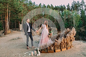 Newlyweds holding hands, laugh and smile, happy and joyful moment. Bride and groom walking on nature. Outdoors wedding