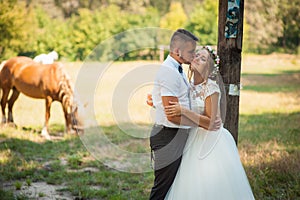 Newlyweds hug standing behind a horse.