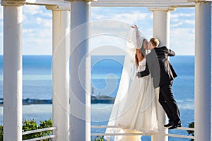Newlyweds kiss in a beautiful gazebo standing on a metal railing