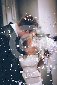 Newlyweds they kiss - intentional defocused image focus on confetti - sensory connections