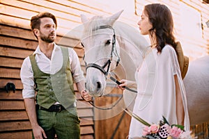 Newlyweds look at each other holding horse