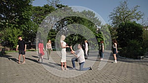 newlyweds, man in love makes an offer to young beautiful woman and puts a ring on his finger backdrop of group of people