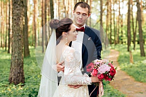 Newlyweds outdoors in the summer park on the background of pines 1