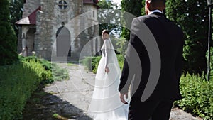 Newlyweds portrait. Lovely Caucasian bride, groom walking near old castle.