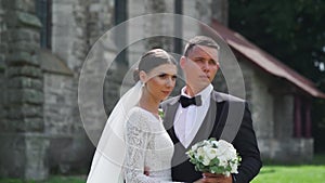 Newlyweds portrait. Lovely Caucasian bride, groom walking near old castle.
