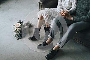 Newlyweds sit at home on the sofa. Legs in casual boots of young couple