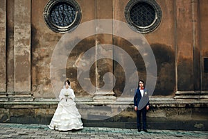 Newlyweds stand apart under the round windows of an old cathedral