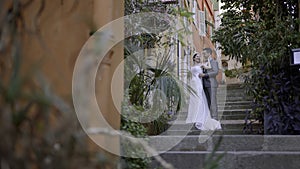 Newlyweds taking pictures on the street. Action. A young couple with a bride in a white dress and a man in a suit who