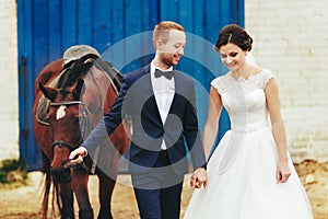 Newlyweds walk with a horse from the stable