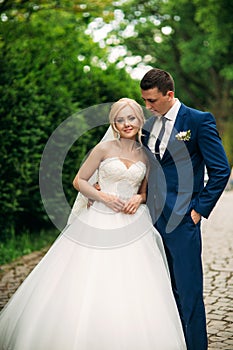 The newlyweds are walking in the park on the wedding day. The bride and groom Enjoying at the wedding day. Sunny weather.