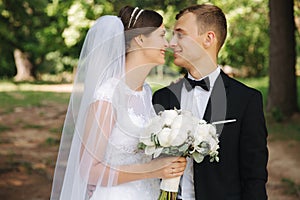 Newlyweds are walking in the park on the wedding day. Just married couple. Groom and bride on green background