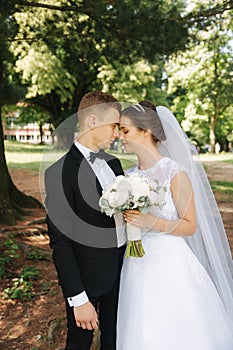 Newlyweds are walking in the park on the wedding day. Just married couple. Groom and bride on green background