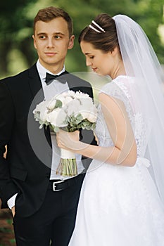 Newlyweds are walking in the park on the wedding day. Just married couple. Groom and bride on green background