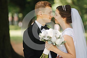 Newlyweds are walking in the park on the wedding day. Just married couple. Groom and bride on green background