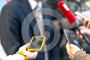 News conference, journalists holding microphone and smartphone interviewing unrecognizable politician or business person during