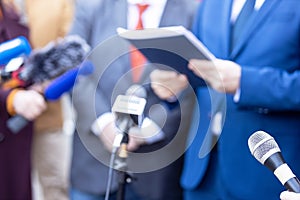 News conference, journalists with microphones interviewing politician or business person during media event