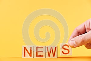 news. hand folds wooden blocks into the inscription news on an orange background.