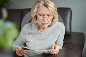 News, press, media, holidays and people concept - woman reading newspaper at home.