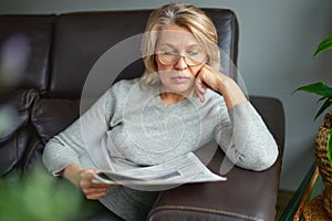 News, press, media, holidays and people concept - woman reading newspaper at home.