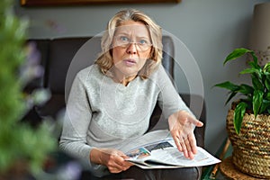 News, press, media, holidays and people concept - woman reading newspaper at home.