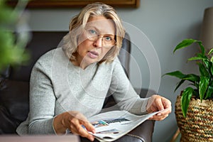 News, press, media, holidays and people concept - woman reading newspaper at home.