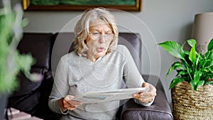 News, press, media, holidays and people concept - woman reading newspaper at home.