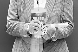 Female journalist at news conference or media event, writing notes, holding microphone