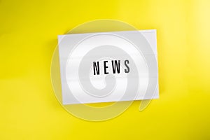 News word on lightbox on yellow background isolated Top view, flat lay