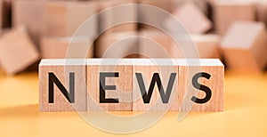 News word made with building wooden cubes on yellow background