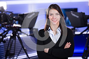 News writing and reporting.Woman journalist in television studio standing with her arms crossed photo