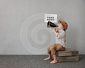 Newsboy shouting against grunge wall background. Boy selling fake news