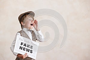 Newsboy shouting against grunge wall background. Boy selling fake news photo