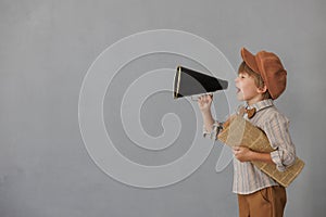 Newsboy shouting against grunge wall background. Boy selling newspaper