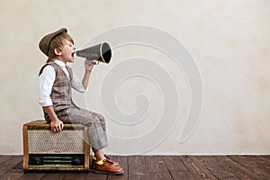 Newsboy shouting against grunge wall background. Boy selling newspaper