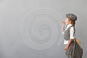 Newsboy shouting against grunge wall background. Boy selling newspaper